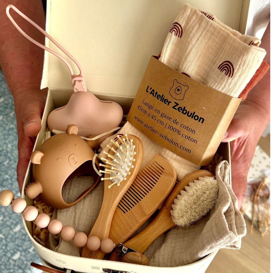Coffret de naissance premium ouvert, articles en silicone, bois et linge de bébé